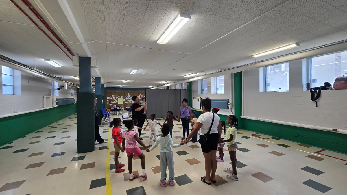 Young children holding hands in a large circle with their teachers during a Little Rhythm Makers class