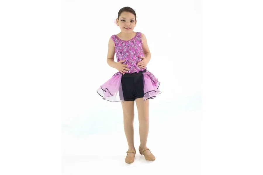 Young dancer in a purple sequined top and tutu skirt standing and smiling